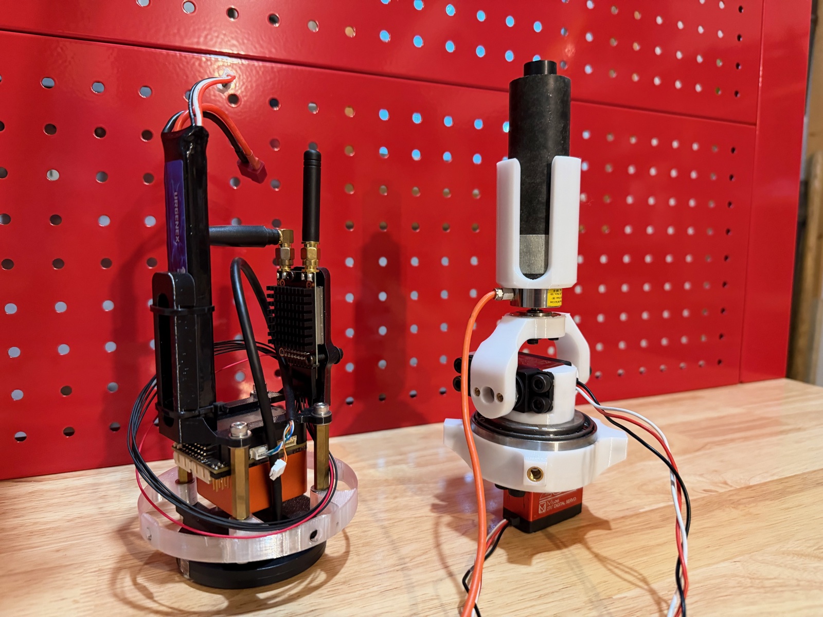 Two electromechanical assemblies on a workbench with red pegboard