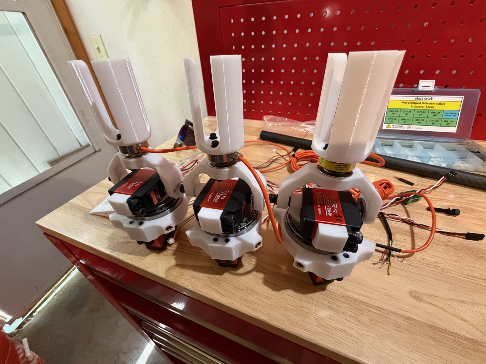 Three servo gimbal assemblies lined up on a workbench